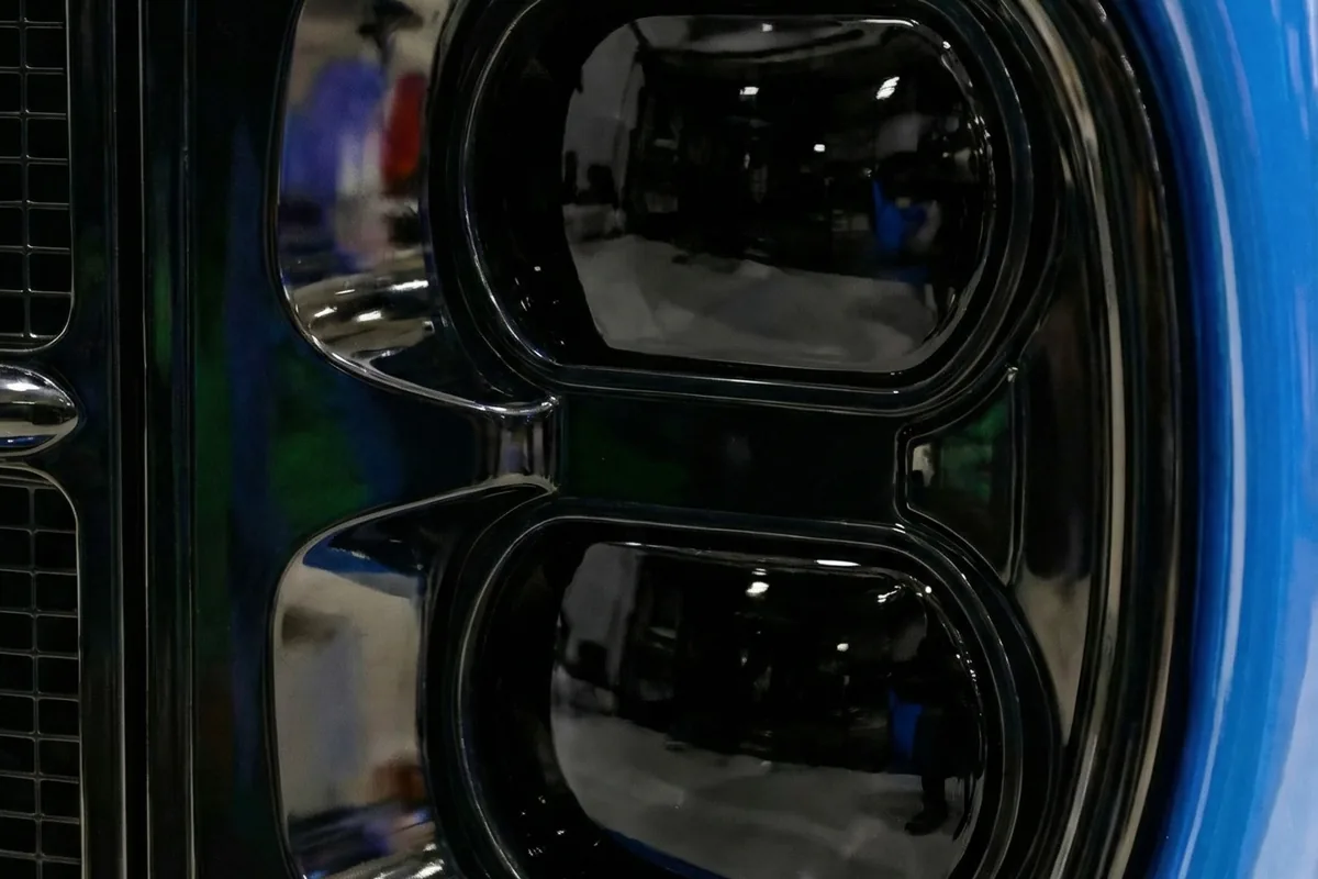Detalhe dos faróis dianteiros escurecidos com lentes de projetor e elementos modernos no Kingpin azul.