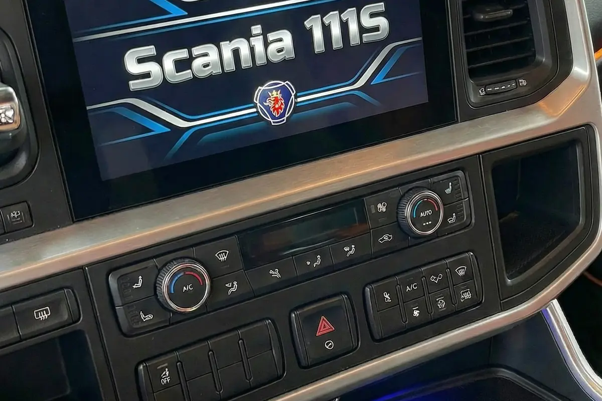 Close-up do console central e tela de infoentretenimento com logo Scania 111S. Controles de clima abaixo.