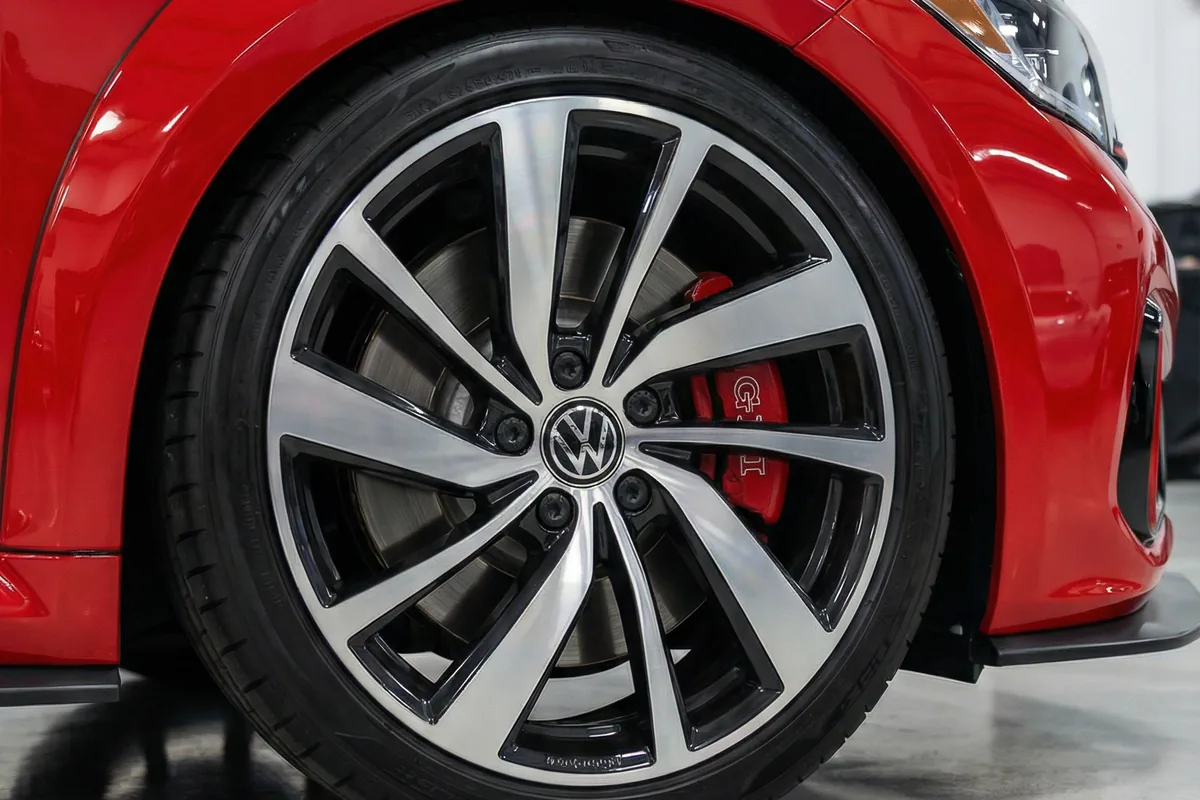 Roda de liga leve multiraio prateada e preta do VW Brasilia GLI Restomod. Pinça de freio vermelha com logo GLI visível.
