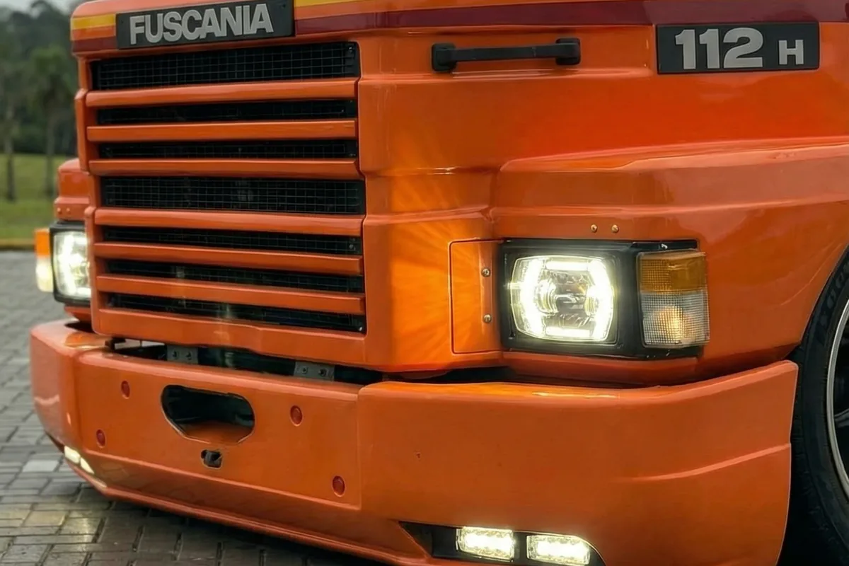 Detalhe da frente do Fuscania 112H, mostrando grade, faróis LED acesos e luzes auxiliares no para-choque.