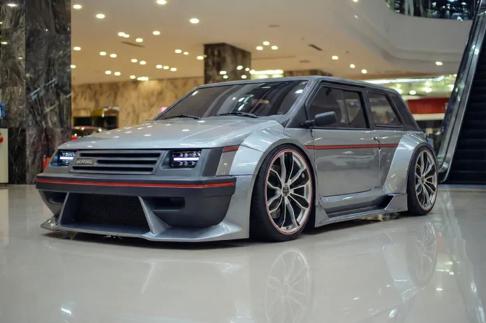 Gurgel BR800 EV restomod prateado com wide body, rodas esportivas e detalhes em vermelho, parado em showroom.