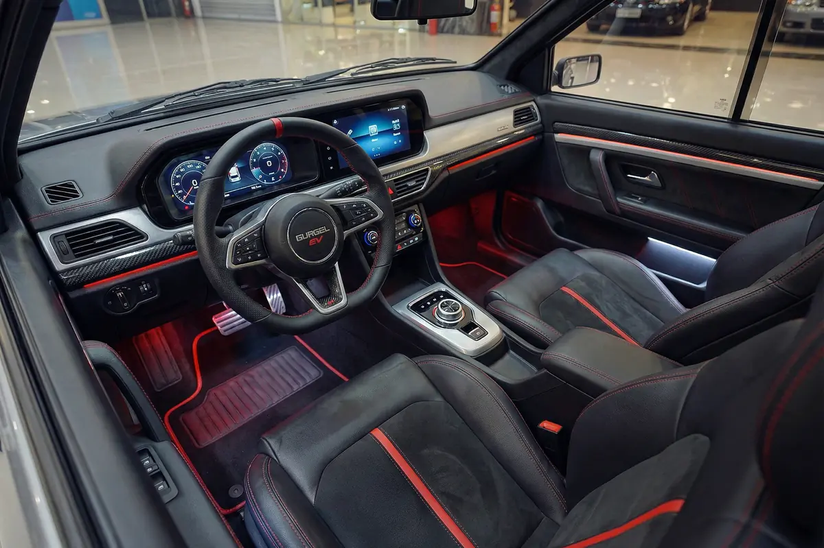 Interior moderno do Gurgel BR800 EV com tela digital, volante esportivo, bancos em couro preto e iluminação vermelha.