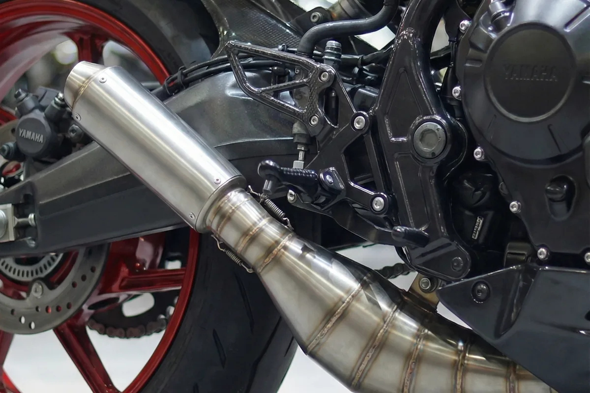 Close-up do escapamento esportivo cromado e roda traseira vermelha da Yamaha RD350 2026 Restomod.