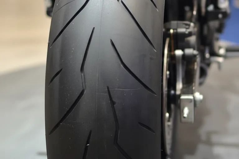 Close-up do pneu traseiro largo com sulcos esportivos da Yamaha XJ6 X em piso de exposição