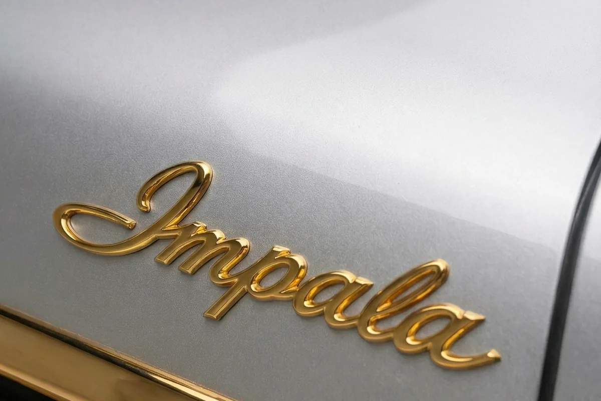Script Impala em letra cursiva dourada, no para-lama dianteiro prata do conceito.