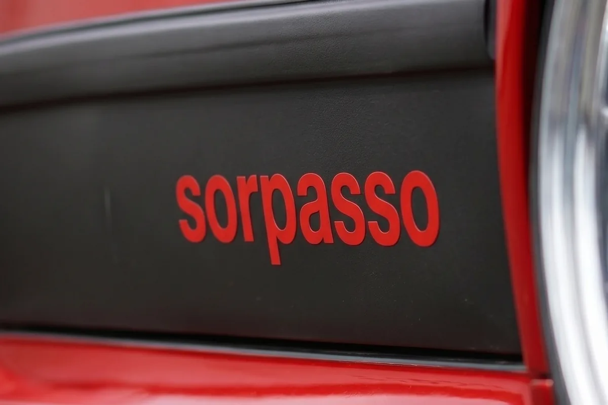 Letreiro sorpasso em letras minúsculas vermelhas sobre a saia lateral preta do Fiat 147 conceito.