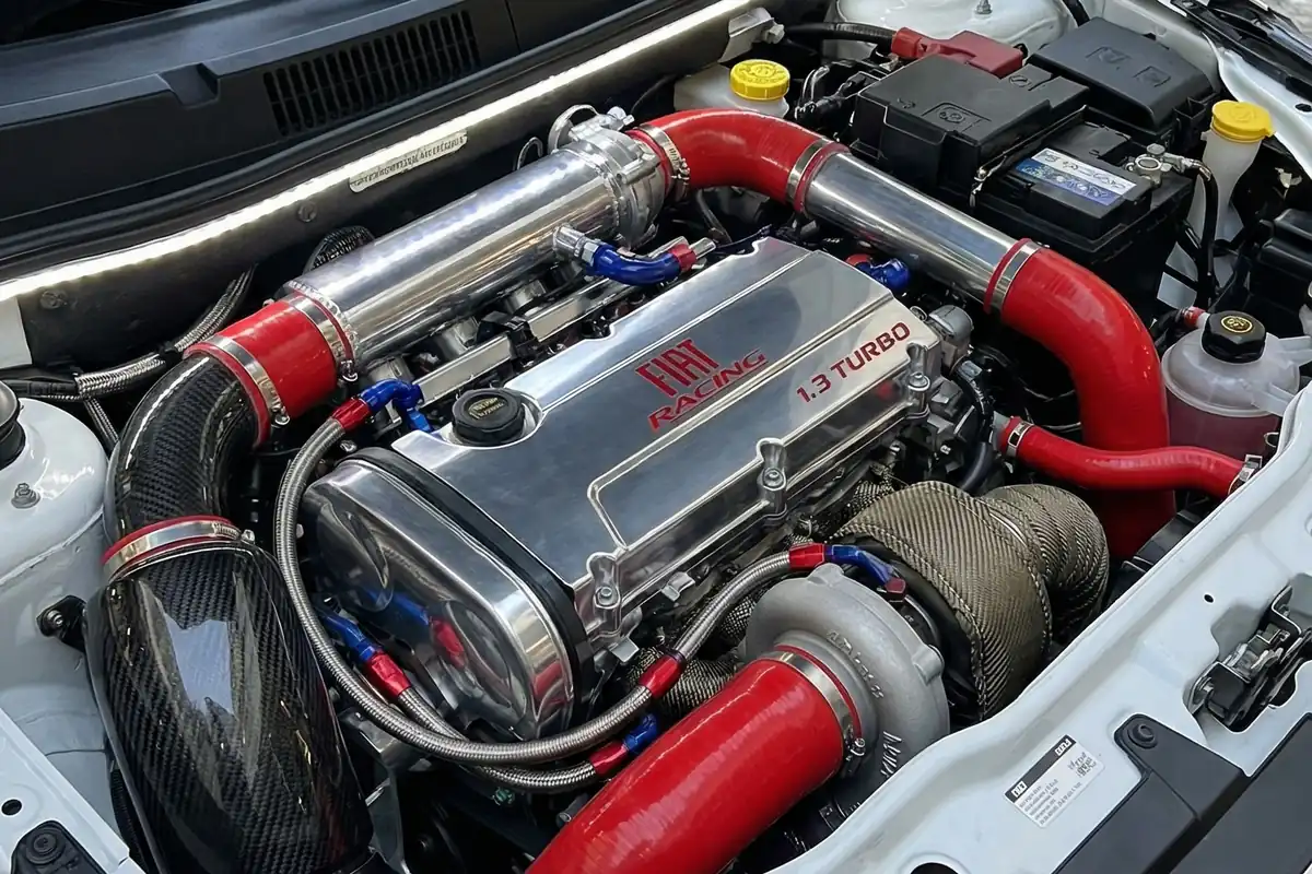 Motor quatro cilindros da Fiorino conceito, com tampa escrita 1.3 TURBO e mangueiras de silicone vermelho.