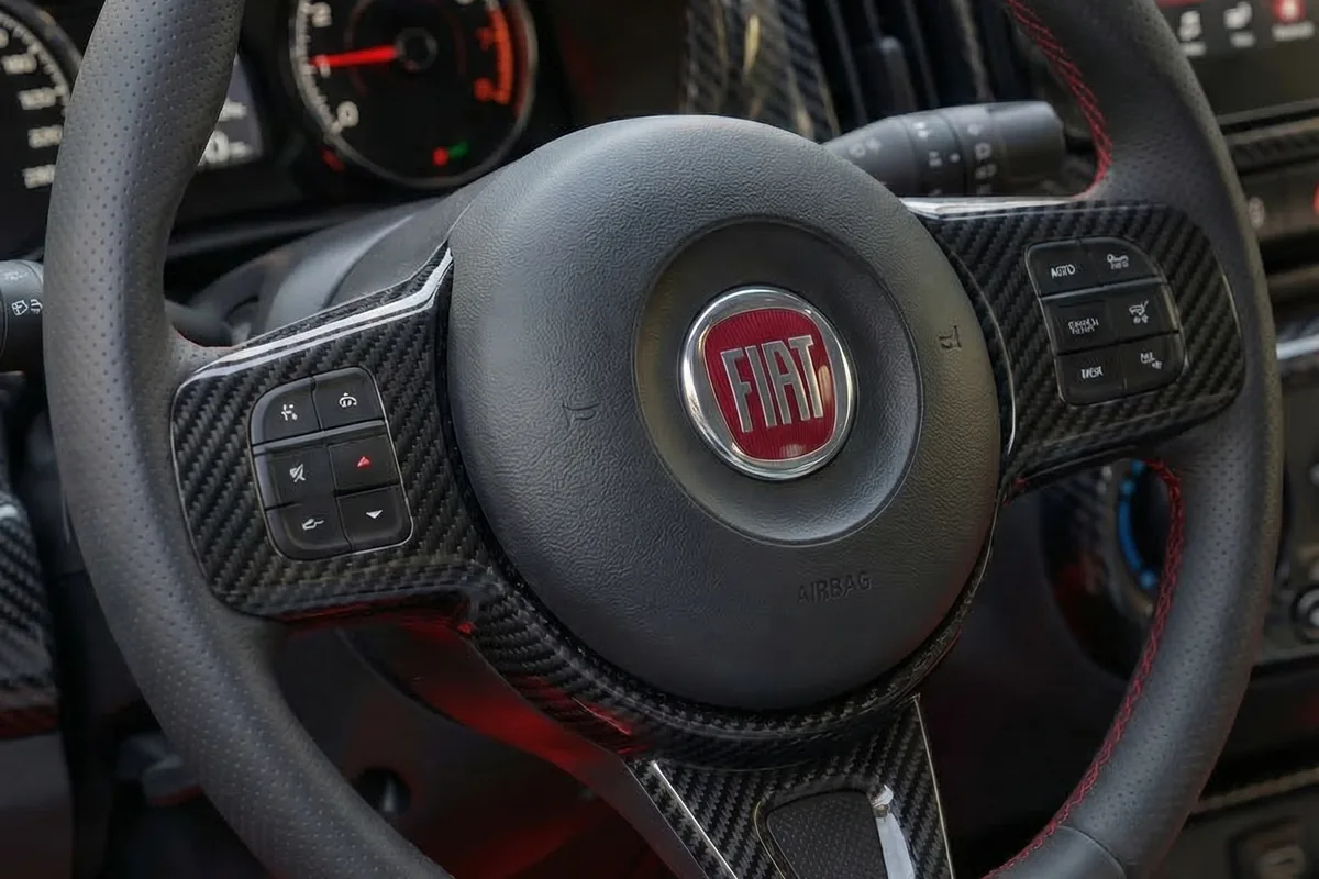 Volante de aro achatado da Fiorino conceito, com emblema vermelho da Fiat e costura vermelha.