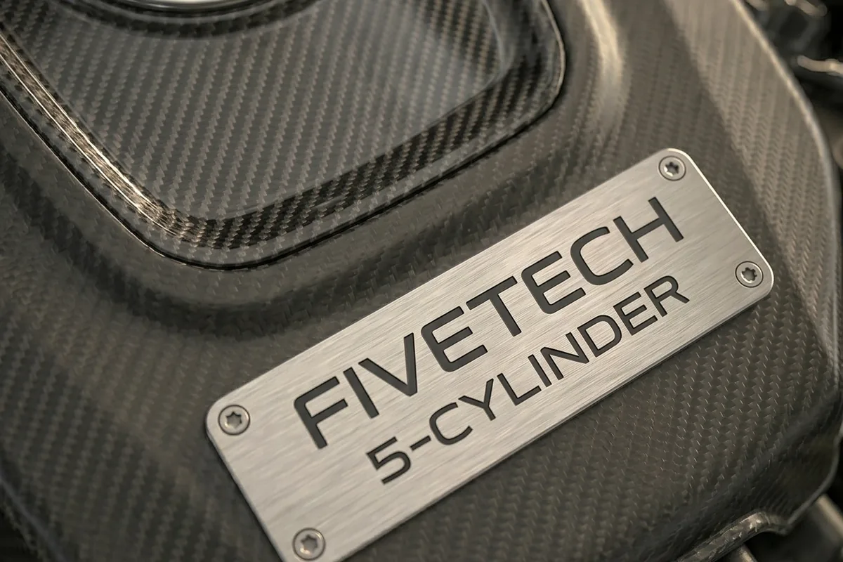 Placa de metal escovado escrita FIVETECH 5-CYLINDER, parafusada sobre a tampa de fibra de carbono.