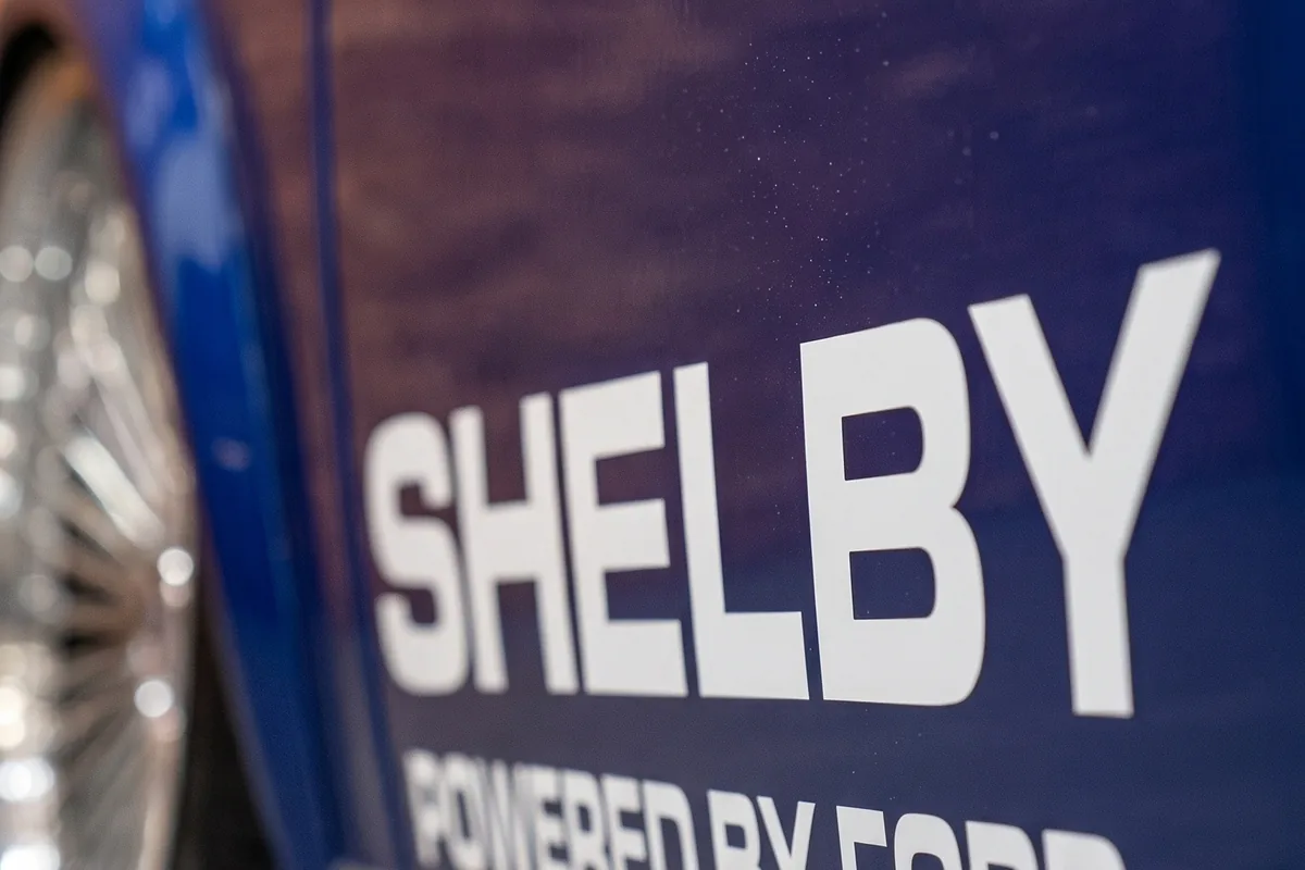 Letreiro SHELBY POWERED BY FORD em letras brancas sobre a lateral azul do Corcel conceito.
