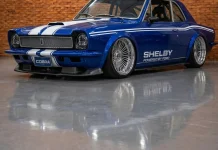 Ford Corcel Shelby: o clássico brasileiro reinventado pela IA com V8 Ford Corcel azul com faixas brancas Shelby em conceito digital, visto em três quartos num galpão de tijolo aparente.