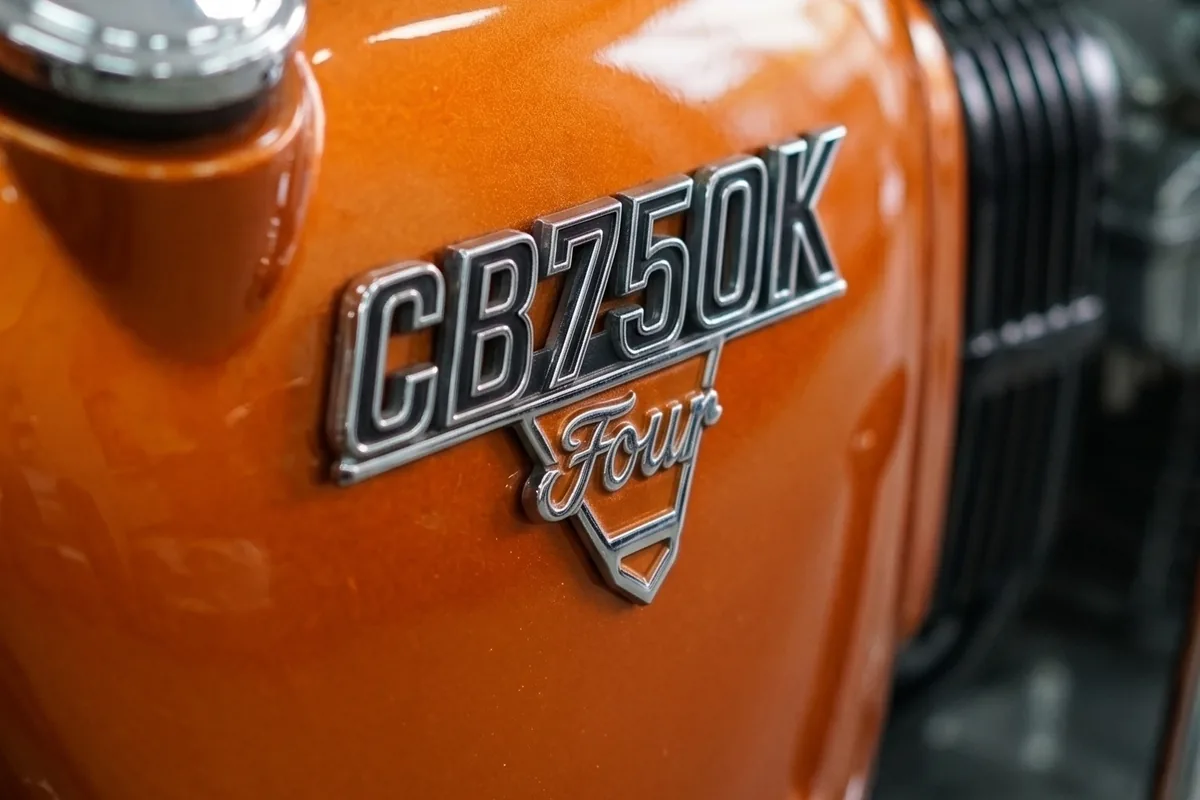 Emblema cromado CB750K Four em relevo sobre o tanque laranja da Honda conceito.