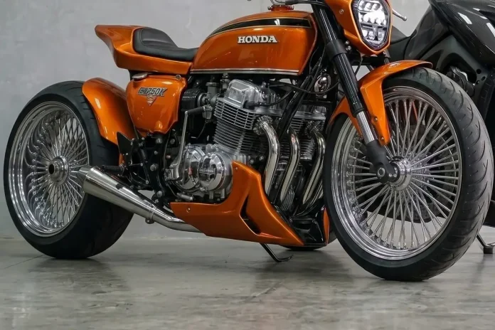 Honda CB 750 laranja metálico em conceito custom, vista lateral em três quartos dentro de uma oficina.