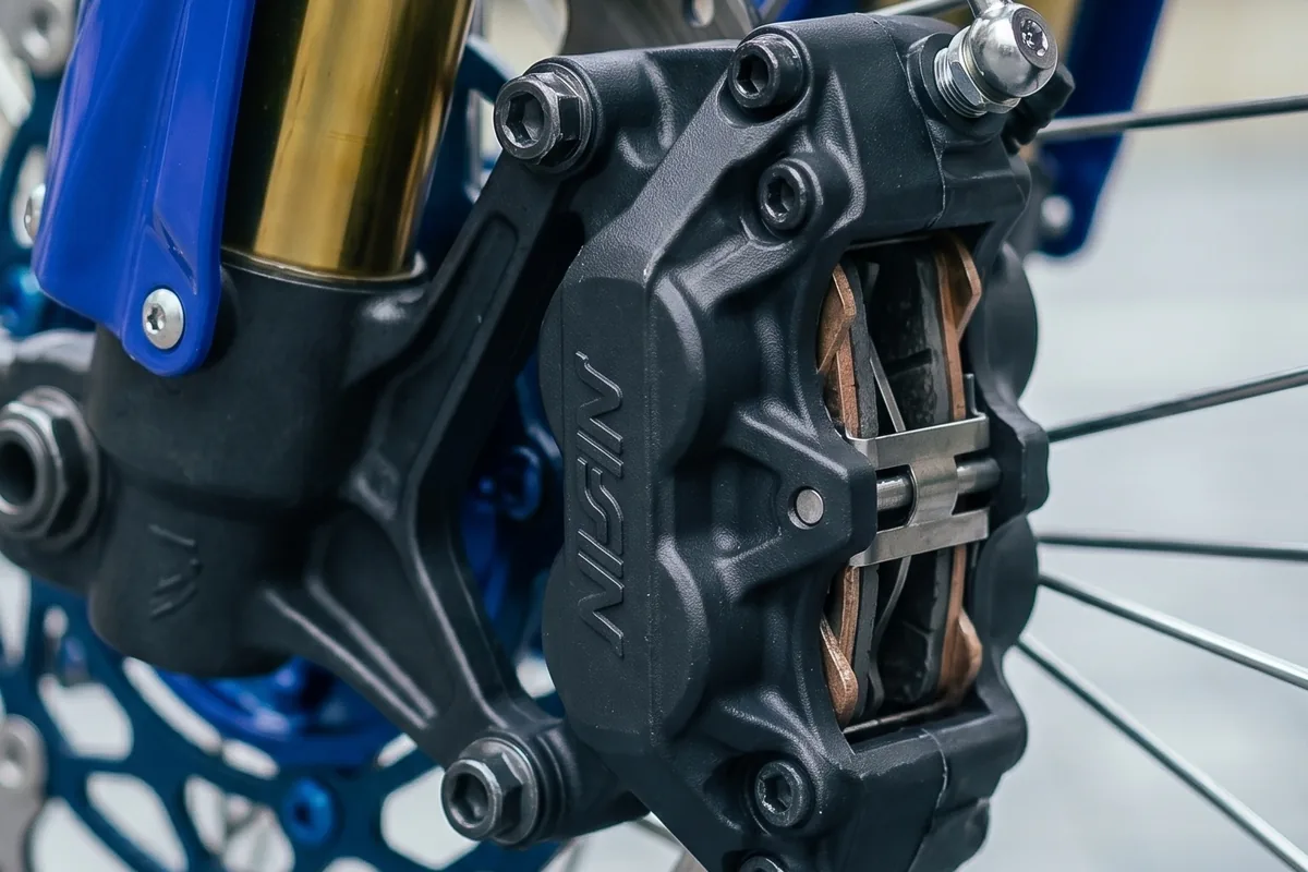 Garfo invertido dourado com disco de onda e pinça radial de quatro pistões.