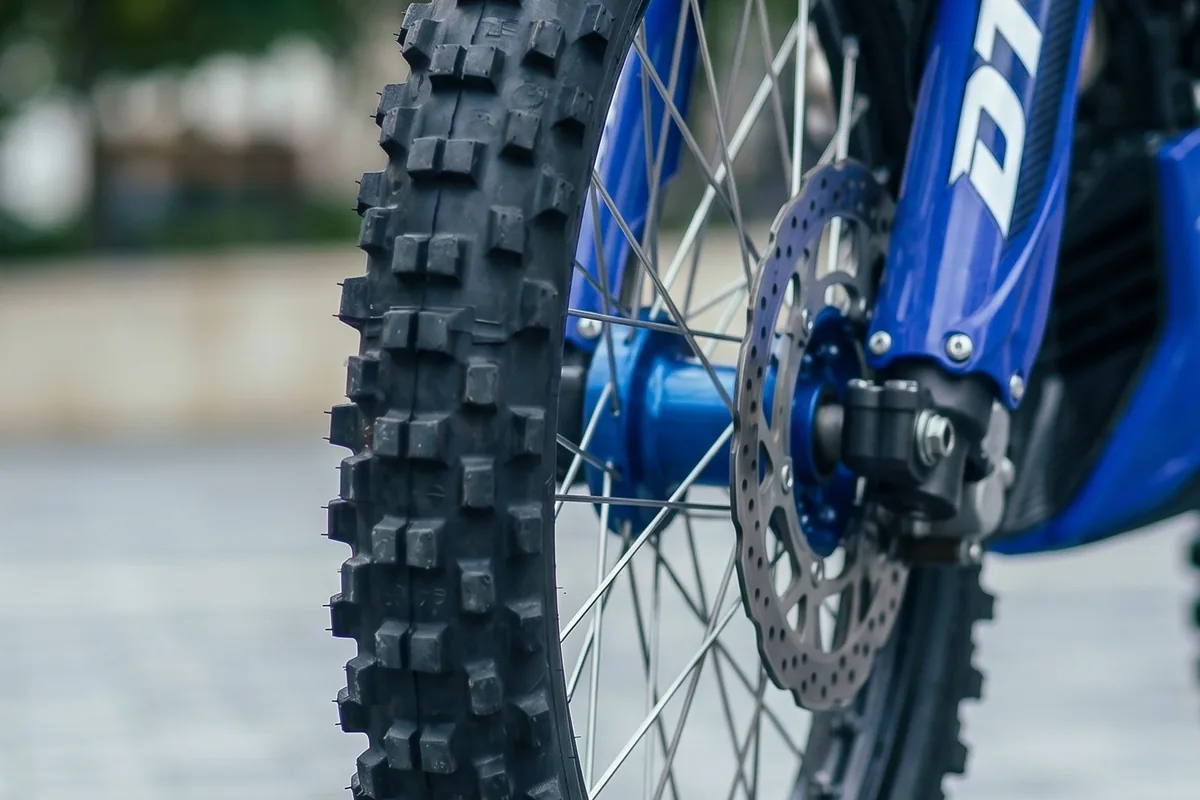 Roda dianteira raiada da DT 400 R, com cubo azul, disco de onda e pneu de tarugo grande.
