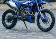 Yamaha DT 400 R: a trail que o Brasil nunca teve, desenhada por IA Yamaha DT 400 R azul em conceito digital, vista de lado numa calçada de pedra portuguesa.