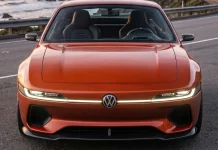 Volkswagen SP2 EV 2027: como seria o clássico brasileiro com propulsão elétrica, segundo a IA Vista frontal do Volkswagen SP2 EV laranja com faixa de LED e logo VW centralizado, em estrada à beira-mar