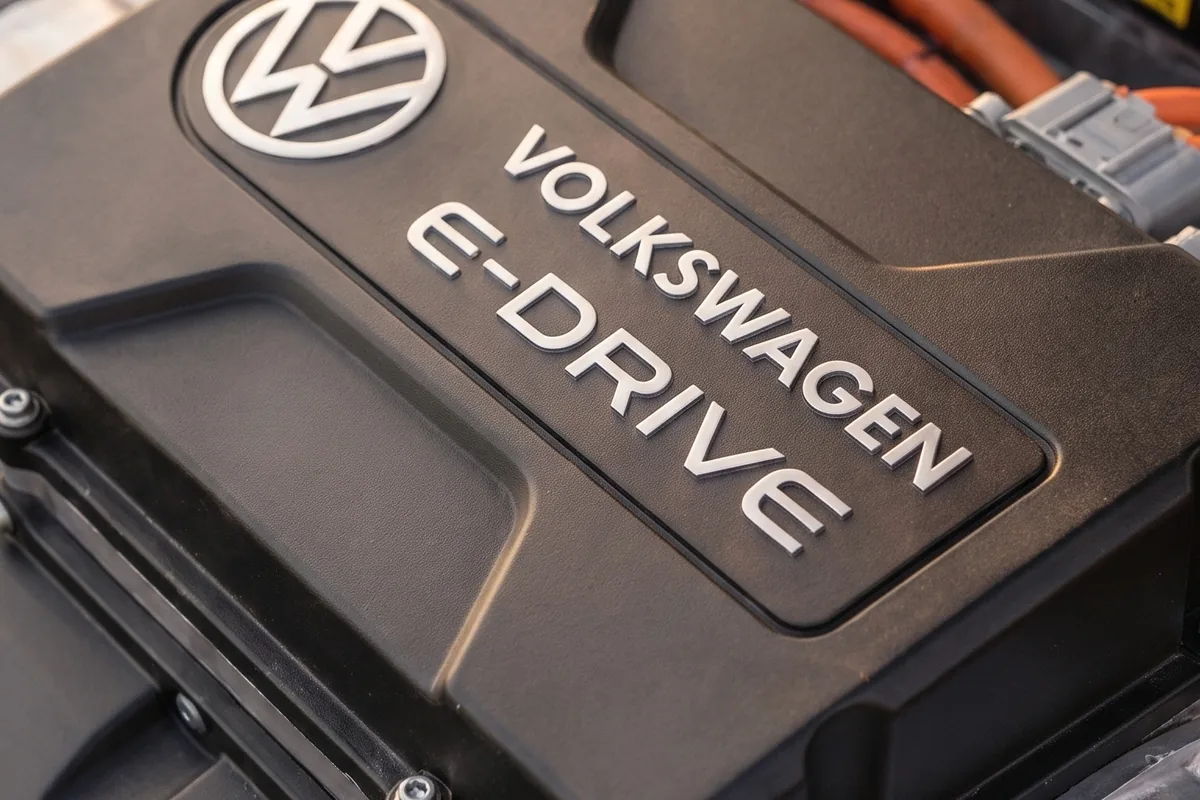 Tampa do motor elétrico Volkswagen E-Drive com logotipo VW e inscrição em relevo sobre fundo escuro