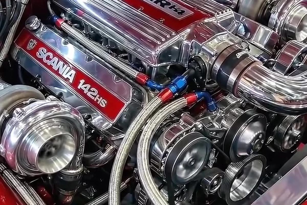 Motor preparado com peças cromadas, turbinas aparentes e tampa vermelha identificada como Scania 142HS.