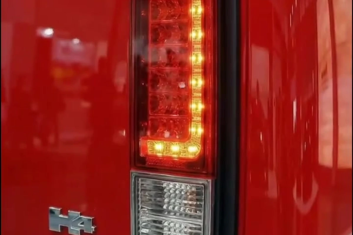 Lanterna traseira vertical acesa na carroceria vermelha, com assinatura luminosa em LED.